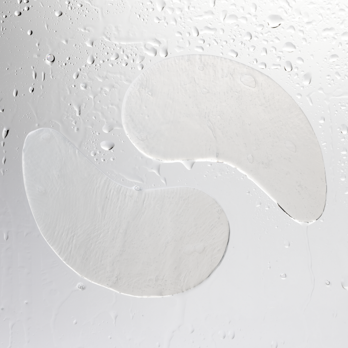 Two translucent HydraRescue Eye Pads on a wet surface with water droplets